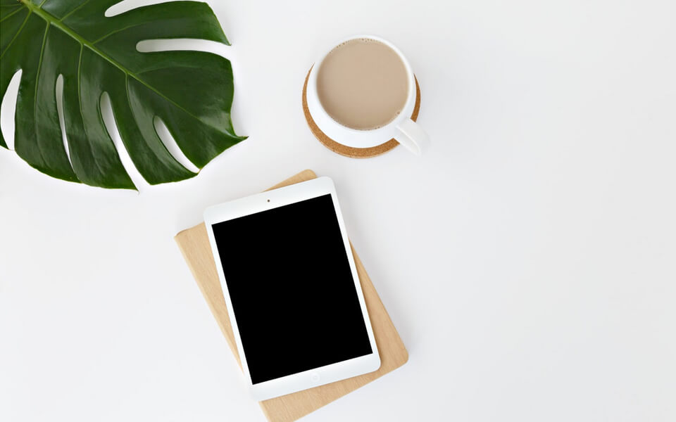 Photo of a tablet and a cup of coffee